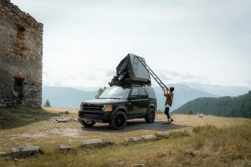 Ein schwarzer Land Rover Discovery 4x4 mit Dachzelt in den Bergen wird vorbereitet.