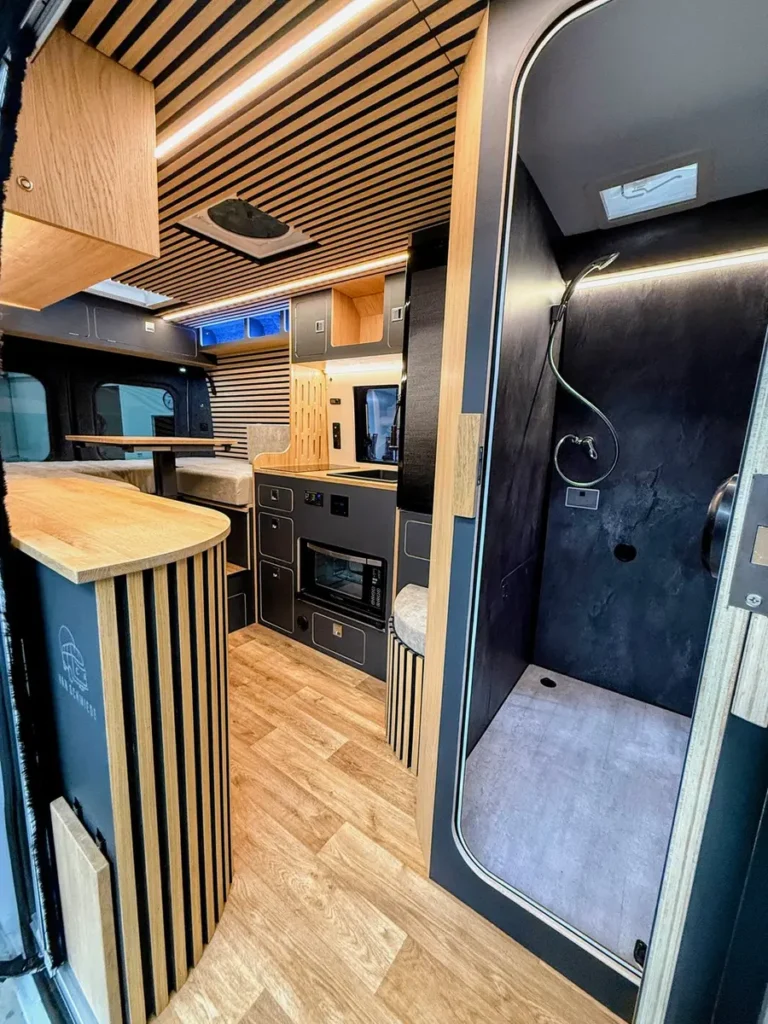 Hochwertiger Vanlife-Ausbau mit Holzelementen, integrierter Küche und separater Dusche.