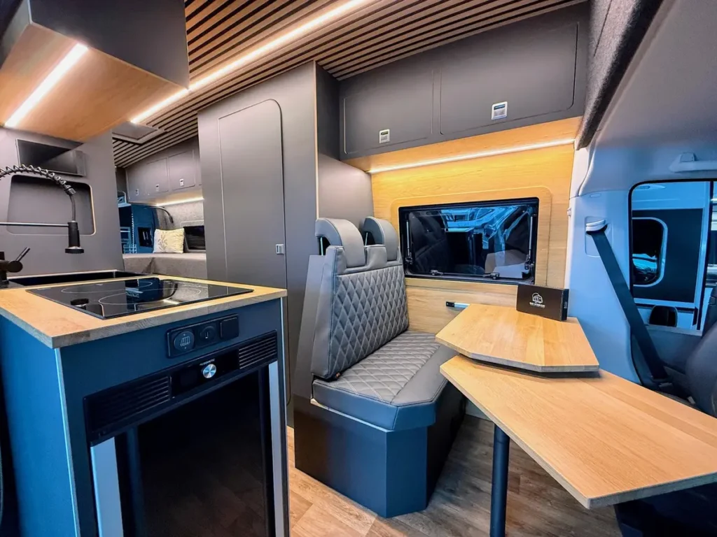 Moderner Campervan Innenausbau mit kompletter Küchenzeile und gemütlicher Essecke.