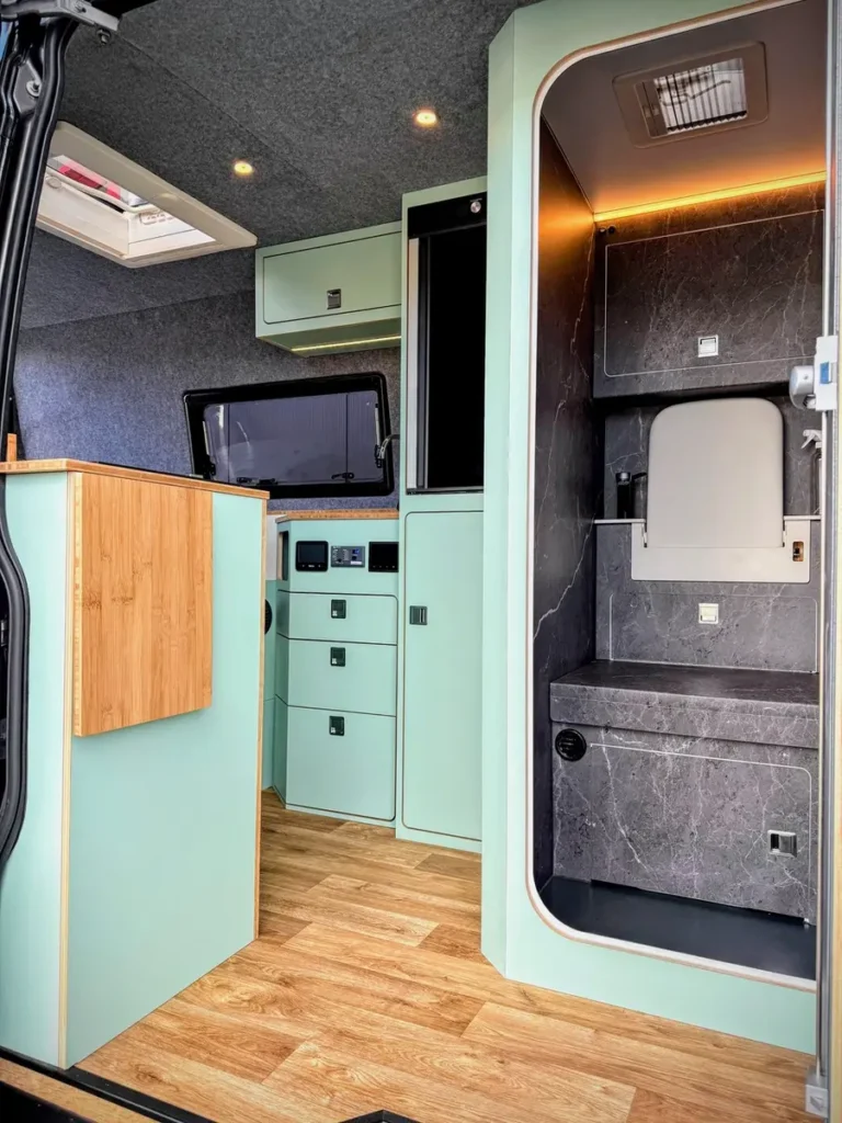 Detailansicht eines modernen Campervan-Selbstausbaus mit hellem Interieur und integrierter Nasszelle.