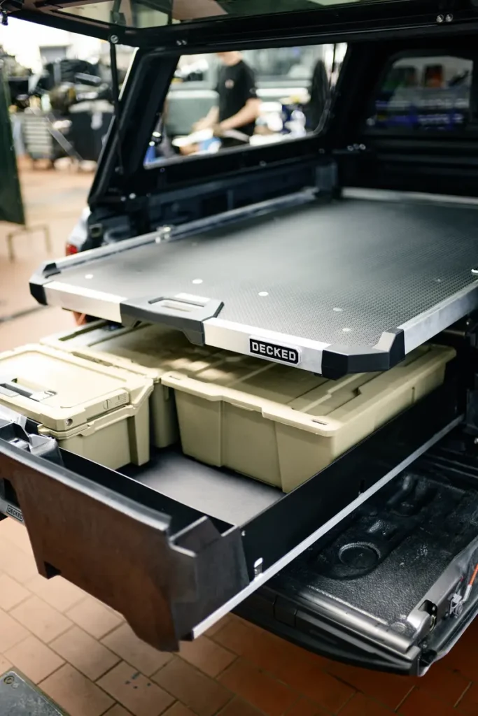 Ein Pickup-Ladeflächenausbau mit ausgezogenem Schubladensystem und beigen Staukisten.